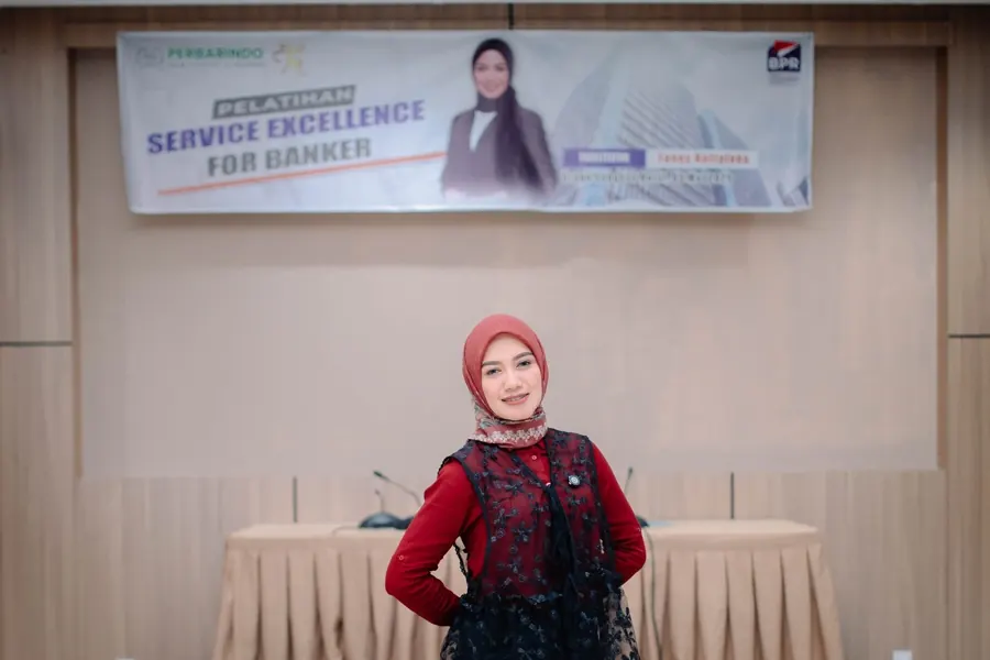 Fanny Naftalena berpose di depan banner pelatihan Service Excellence for Banker Perbarindo Komisariat Cirebon
